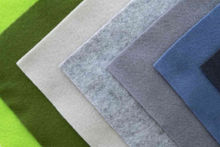 Pieces of coloured carpets that move seamlessly from black through grey to light green. The rugs are made of a similar-looking material.